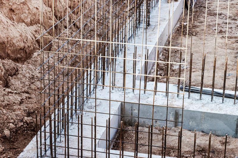 Reinforcement cages tied in a strip footing excavation, ready for a concrete pour.