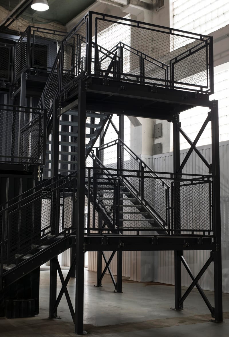 A black steel stair and platform frame inside a steel-framed structure.